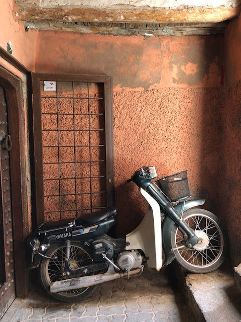 Motorcycle resting in salmon colored entryway.