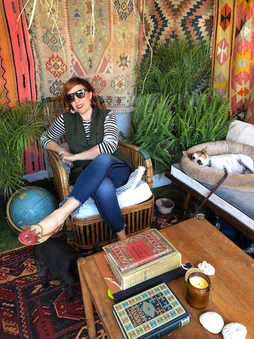 brimfield antique market customer in womens velvet slides and womens kilim loafers surrounded by kilim carpets and mens kilim loafers.