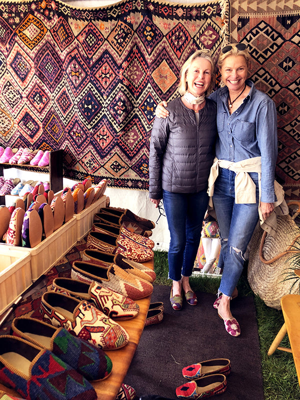 customer at brimfield antique market with womens kilim shoes surrounded by kilim carpets and mens kilim loafers.