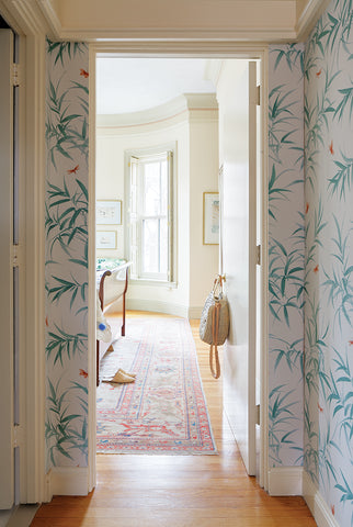 milicents hallway with leafy wallpaper, raffia marché bag. View into milicents room with raffia babouche shoes on a red kilim carpet.