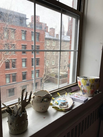 view from paulines apartment window with vases and sculptures lining the ledge of the window.