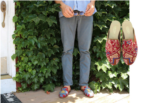 Model Lincoln in blue tones with mens kilim slippers in front of green plant. 