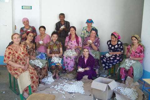 photograph of silk ikat weavers in uzbekistan in colorful dresses and headscarves.