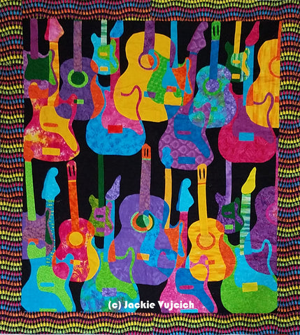 Guitars in many viabrant colors are depicted in this quilt made and  featured in a blog post by Jackie Vujcich of Colorado Creations Quilting
