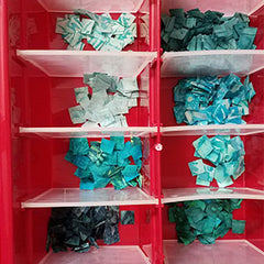 Tiny aqua blue half-inch squares separted by color in an ornament container.