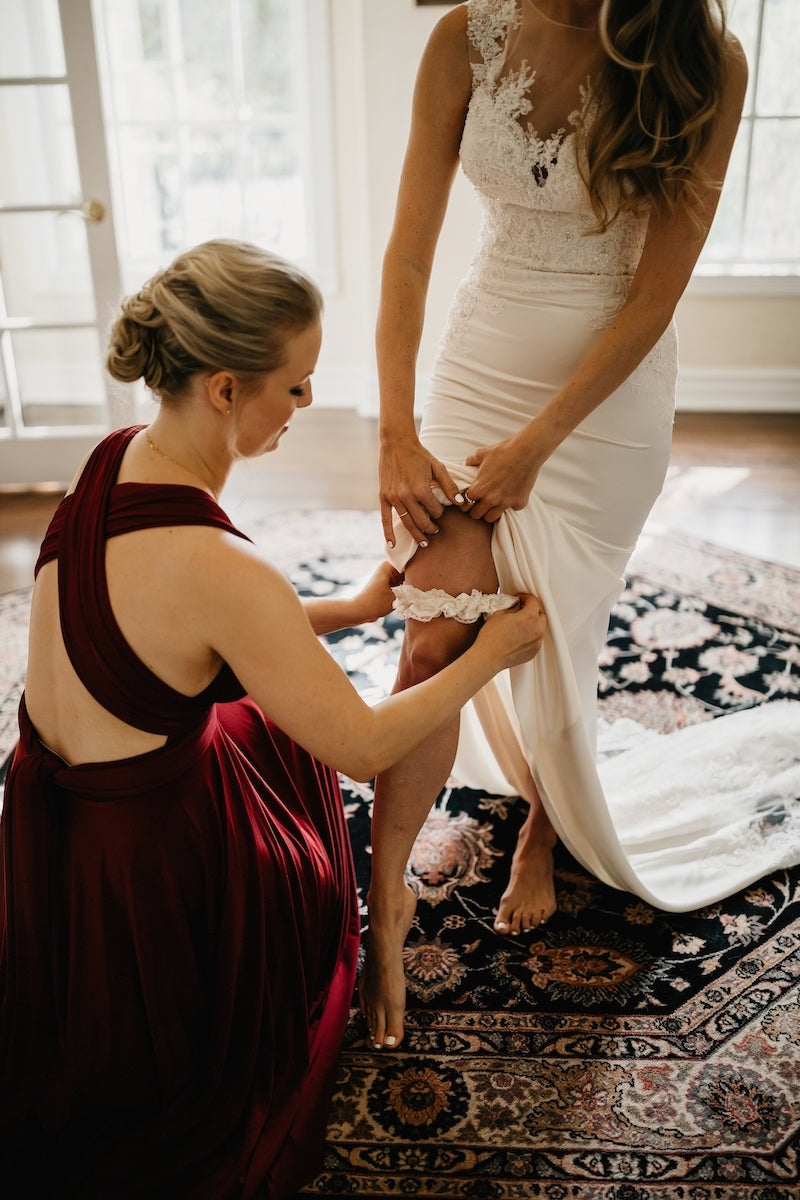 bridesmaid helping bride put on family heirloom garter