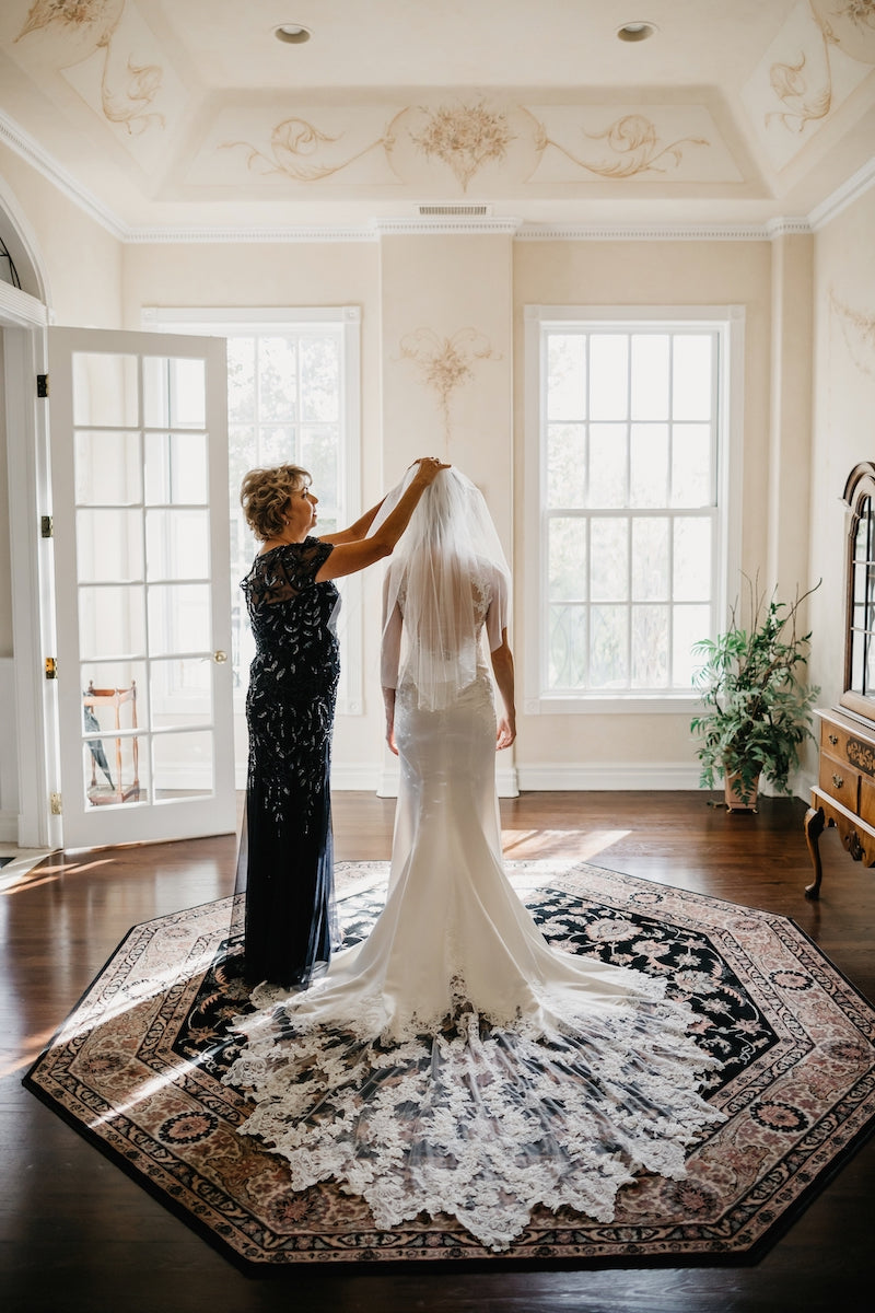 mother helping bride put on veil