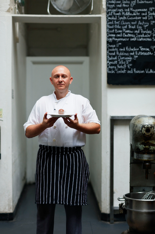 Chef standing outside restaurant holding ice cream on plate
