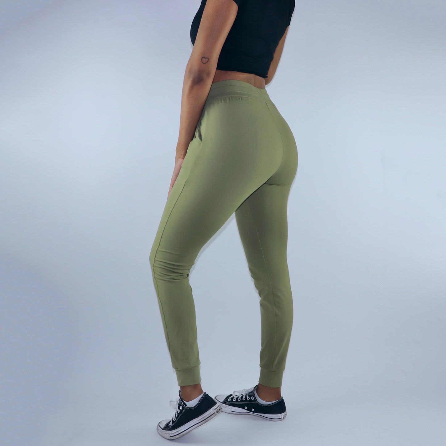Side view of women's dark green joggers with 2 side pockets. Cuffed ankles and mid waist rise.