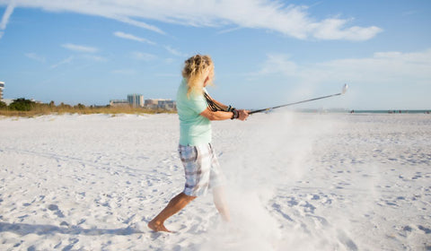 Male golfing on beach