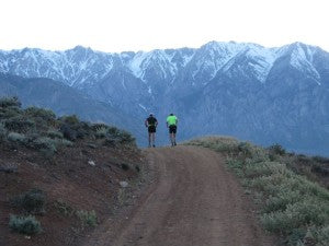 two runners on a trail in the mountains