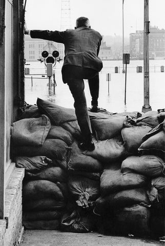 Man standing on sandbags during extensive flooding, 1965. -- Quad-City Times