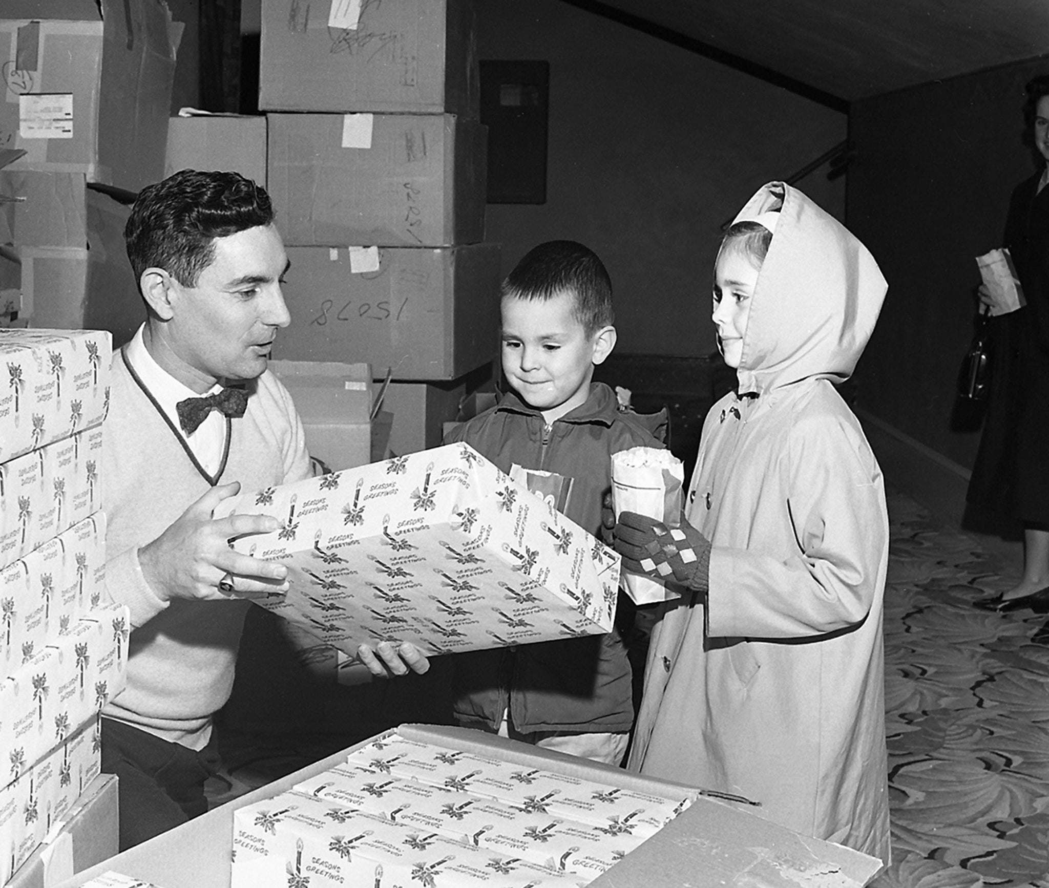 Bob Hammond from Longview Fibre’s accounting department, giving two children a Christmas gift at a Longview Fibre Christmas party at the Columbia Theater, December 21, 1963. -- COWLITZ COUNTY HISTORICAL MUSEUM / #2010.0054.0162
