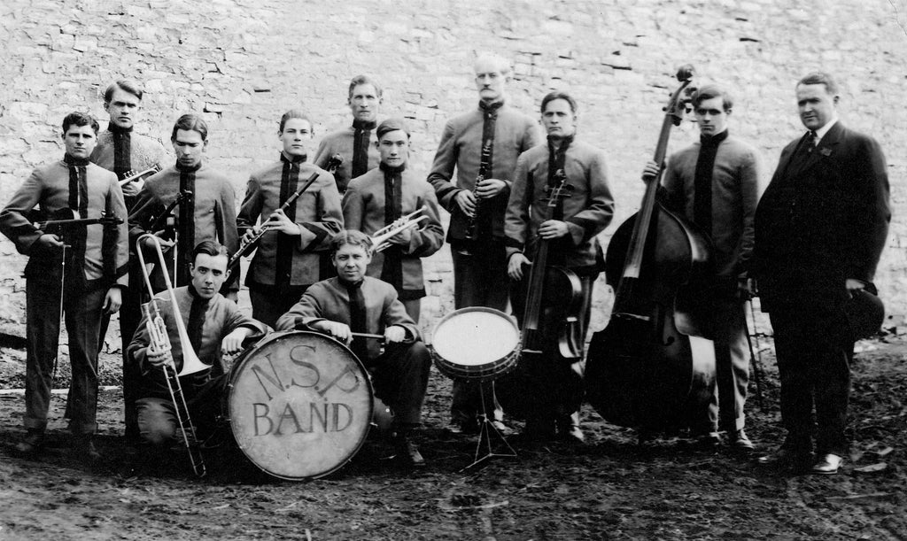 The 11-piece Nebraska State Penitentiary Band, circa 1918. All band members were inmates serving time. William T. Fulton, the warden, stands on the right holding a bowler hat. -- Nebraska State Historical Society