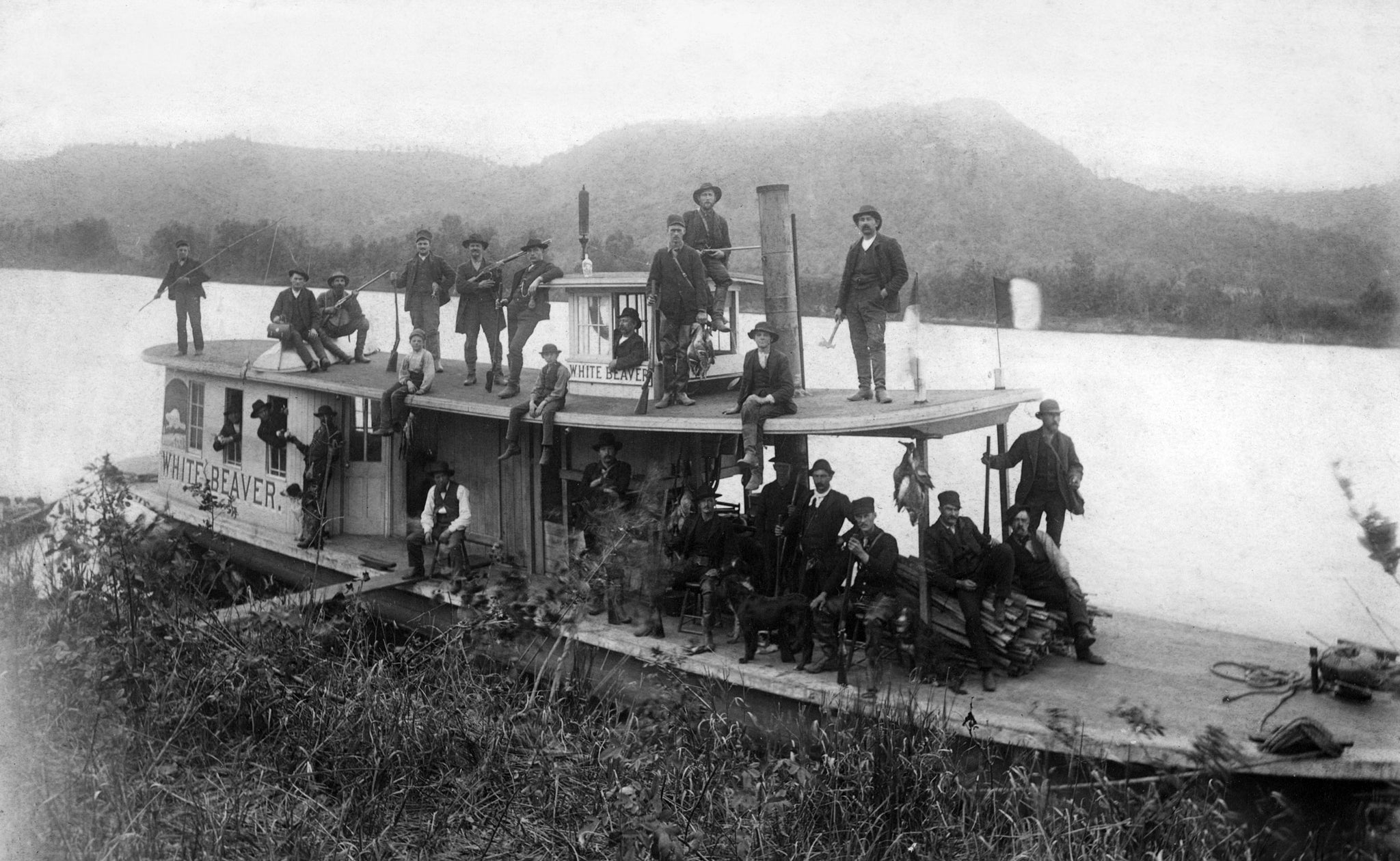 A hunting party on the steamboat White Beaver, circa 1900. The boat belonged to G. L. Winslow, who can be seen sitting on the wood pile. His son, E. M. Winslow, is on the left. -- COURTESY UNIVERSITY OF WISCONSIN-LA CROSSE / #17260
