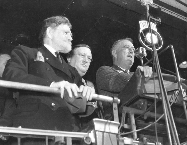 Franklin Roosevelt speaking to a Bloomington crowd from the platform of his train, 1936. J. Hamilton Lewis is at the far left and Edward Hughes is in the middle. -- The McLean County Museum of History, Pantagraph Collection