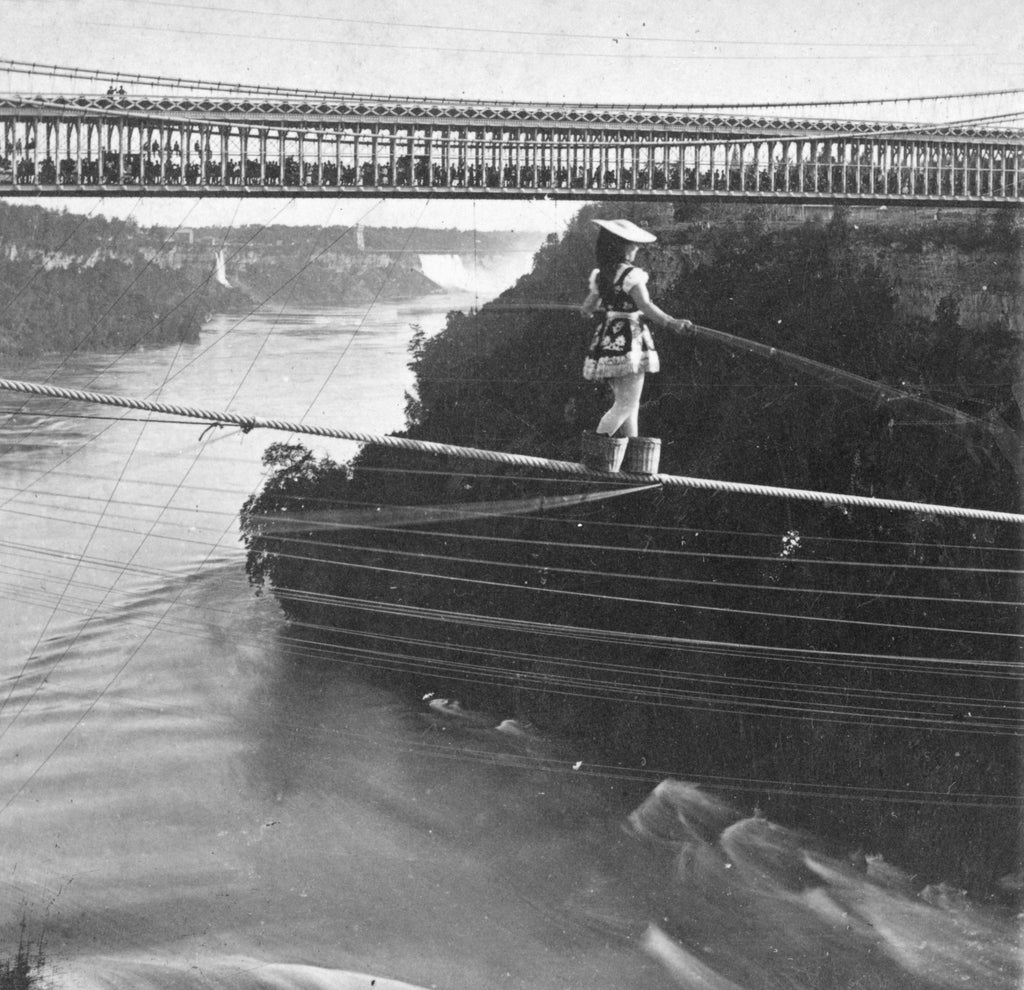 Maria Spelterini crossing Whirlpool Rapids on a high wire with peach baskets on her feet. -- Niagara Falls Public Library