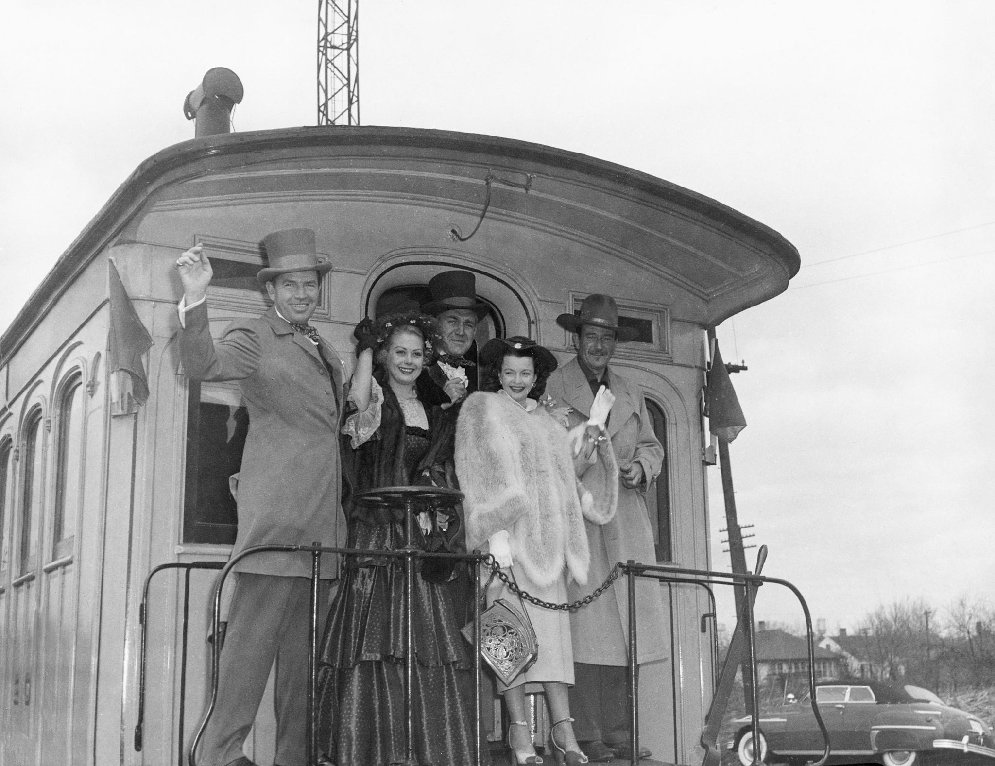 From left: Forrest Tucker, Adele Mara, Bruce Cabot, Dale Evans and John Wayne wave from the back of a train after the world premier of “Rock Island Trail” at three Quad-City movie houses, 1950. -- Rock Island County Historical Society