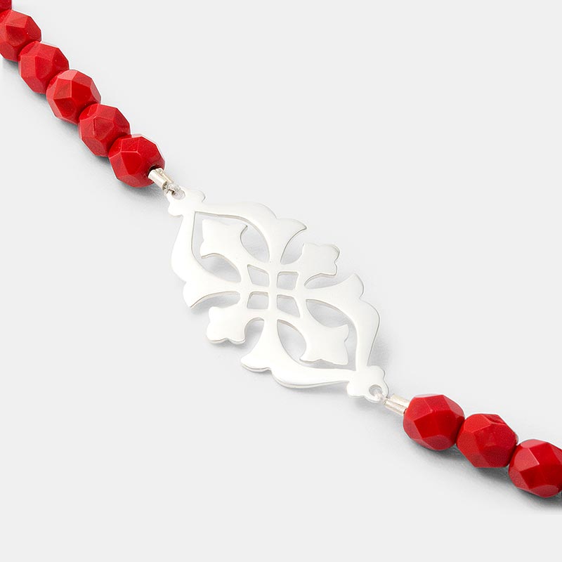 Intricate saw piercing in our sterling silver arabesque necklace with red beads.