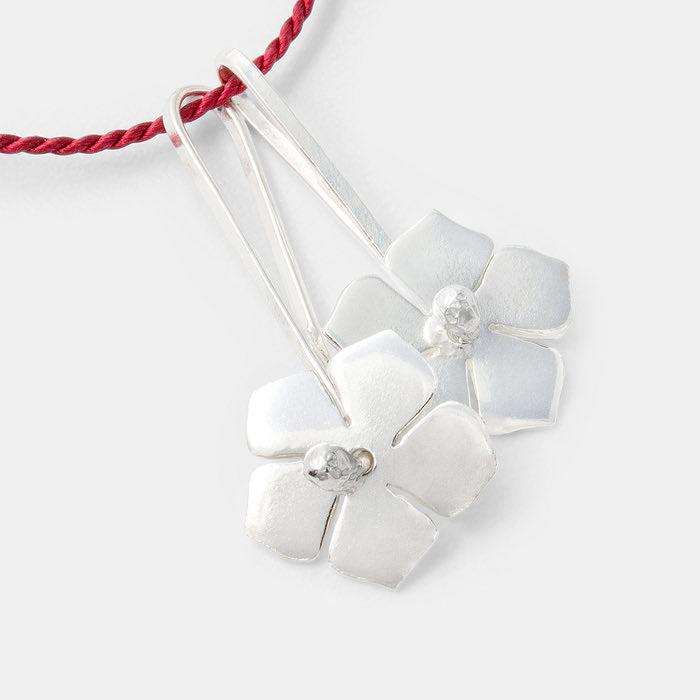 Sterling silver forget-me-nots pendants on red silk necklace.
