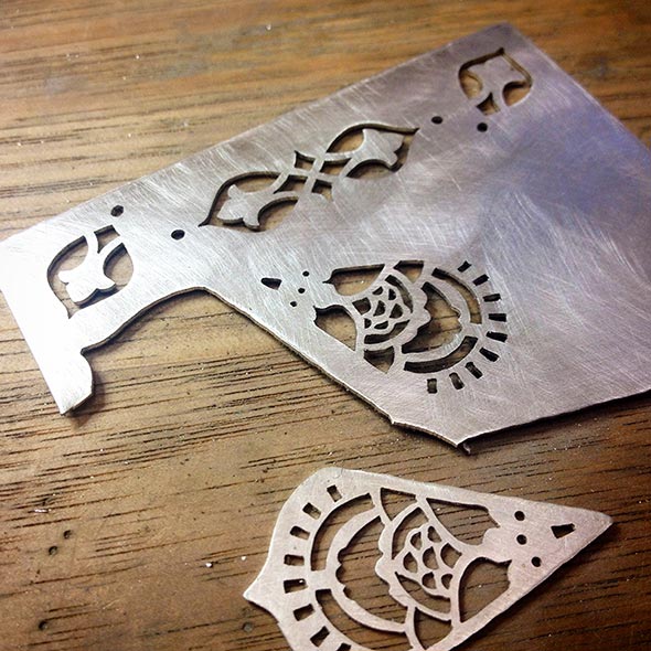 Fretwork sawn into sterling silver sheet with a fine jeweller's saw before the outlines are cut out.