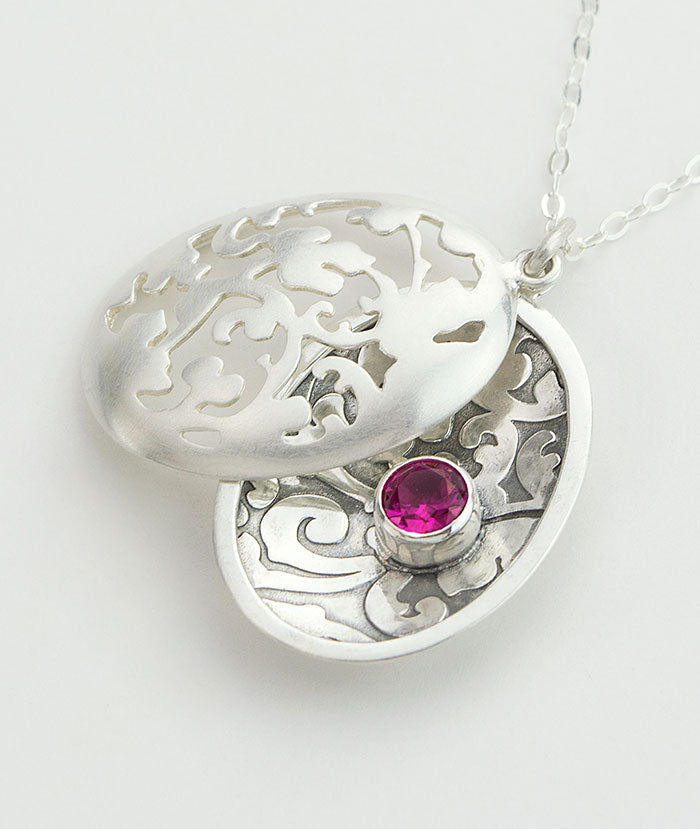 Victorian leaves open locket in sterling silver with a ruby gemstone.