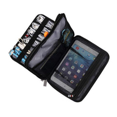 Black travel electronics organizer with showcasing the many compartments to house cables, cords, and an ipad when traveling. Photo by plentiful travel, travel products.
