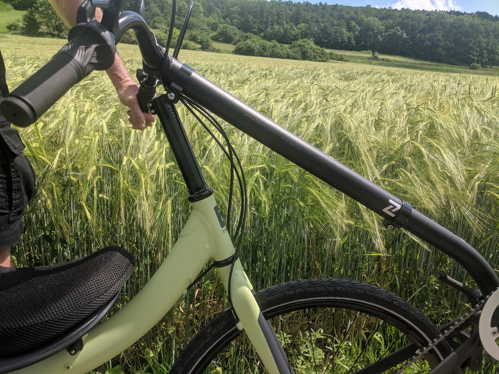 Photo of Jim holding his Cruzbike Q45 touring recumbent bicycle in front of a gorgeous sunny wheat field
