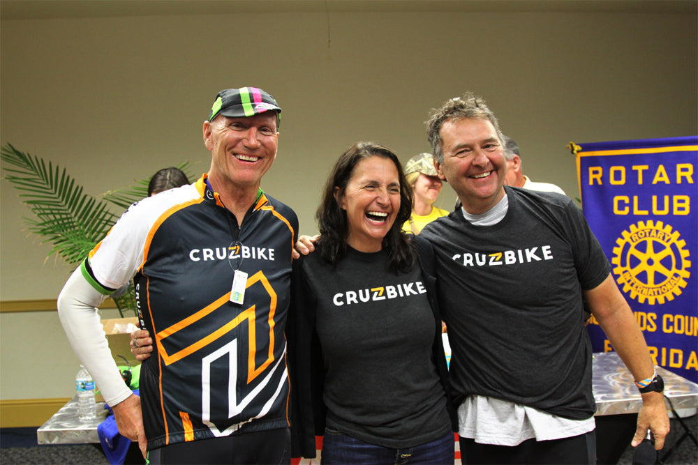Cruzbike's CEO, Maria Parker, flanked by rival CEOs both wearing Cruzbike colors.