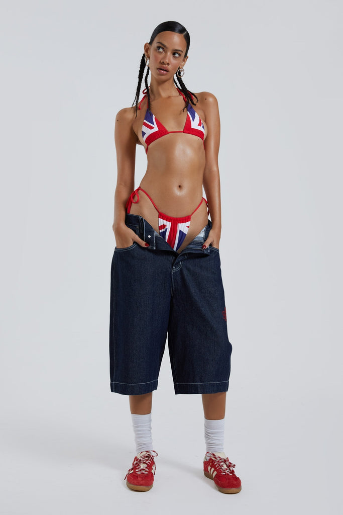 Female wearing sandblast washed denim oversized jorts in a jumbo fit with embroidered pocket patch detail.
