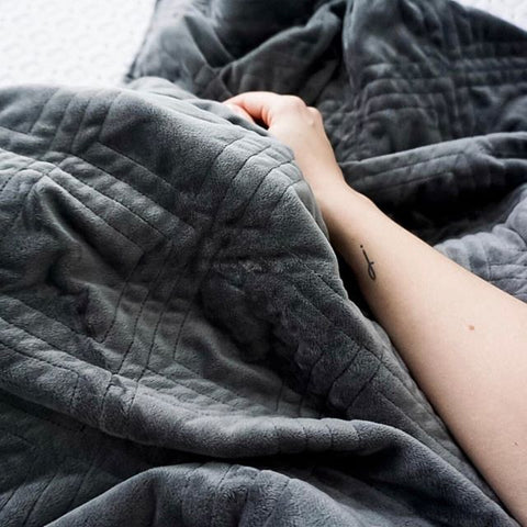 hand resting on a dark grey weighted blanket