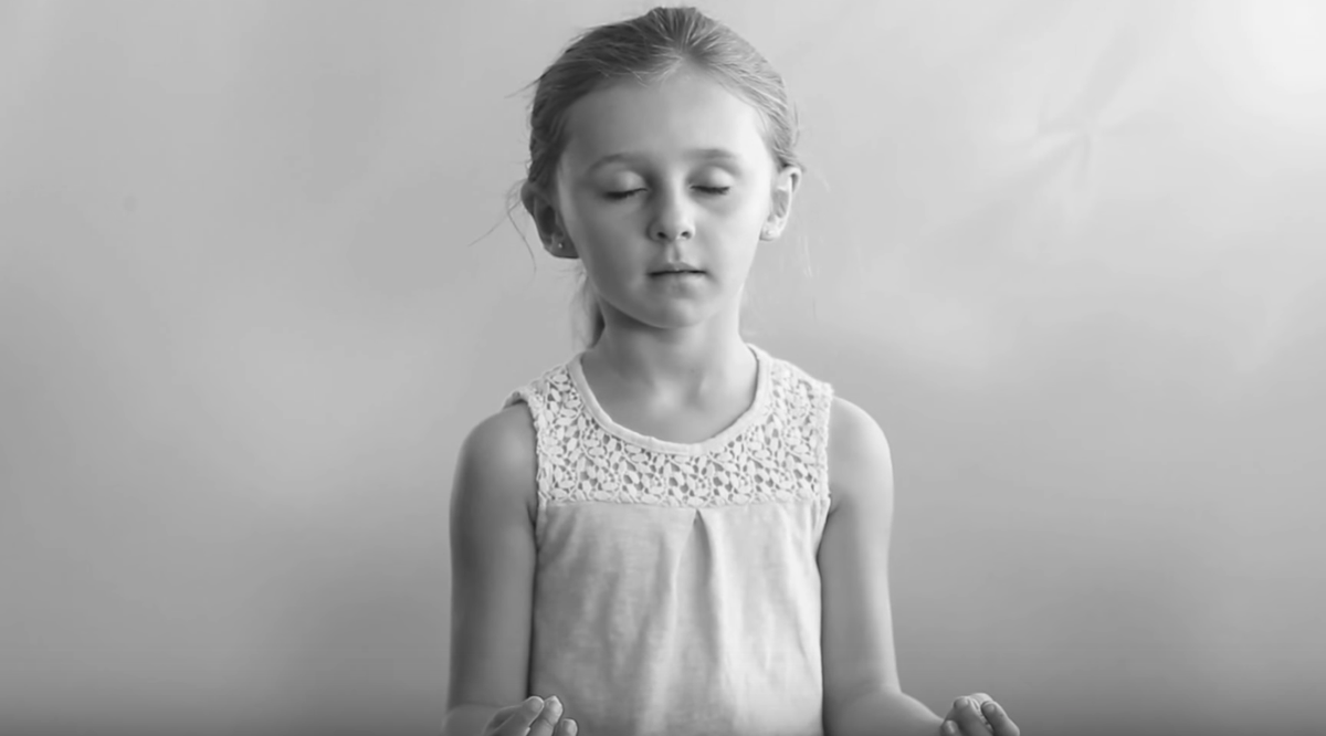 little girl closing her eyes and meditating