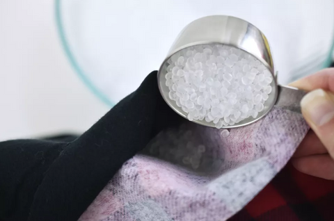 poly pellet fillings in a measuring cup being poured inside a weighted blanket
