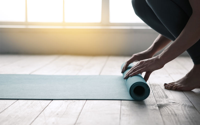 Woman rolling out yoga mat in the morning