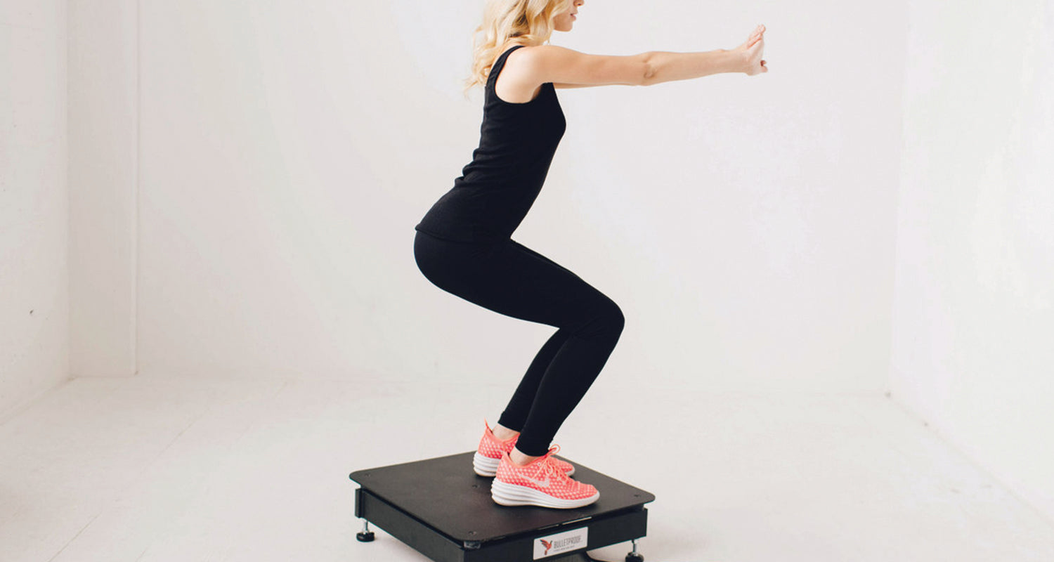 Woman doing squats on a vibration plate exercise machine