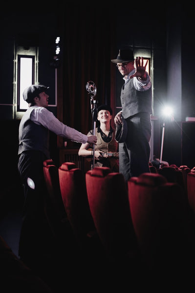 The Bad Mouse Orchestra in einem Kinosaal mit roten Plüschsesseln, Stefan Pößiger streckt die Hand zur Kamera aus