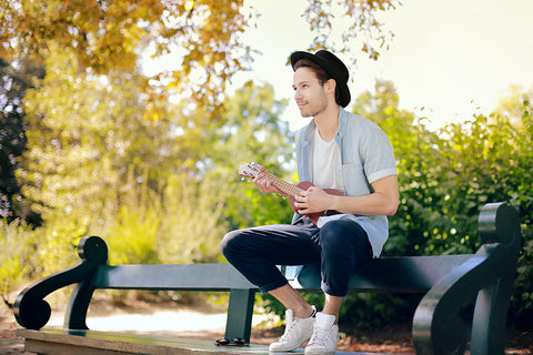 Junger Mann mit Ukulele im Park