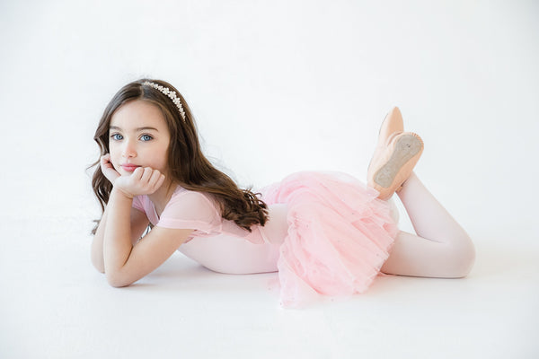 Little ballerina lying on the floor in a tutu with leather ballet shoes on