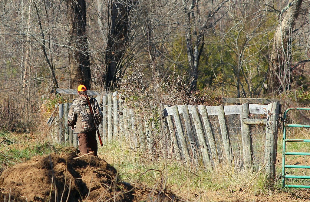 Man walking along a fence while deer hunting.