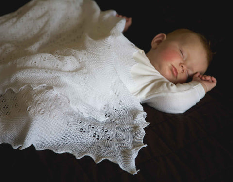  sleeping baby beneath a christening shawl