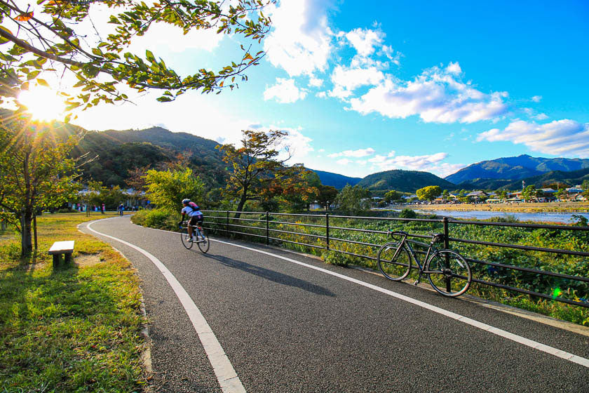 A cyclists riding along the cycling path on the Katsura river in Arashiyama, Kyoto.