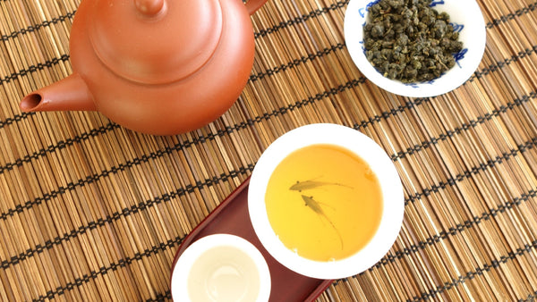 Yixing Teekanne mit Oolong Tee in einer Tasse auf einem Bambus Untersetzer