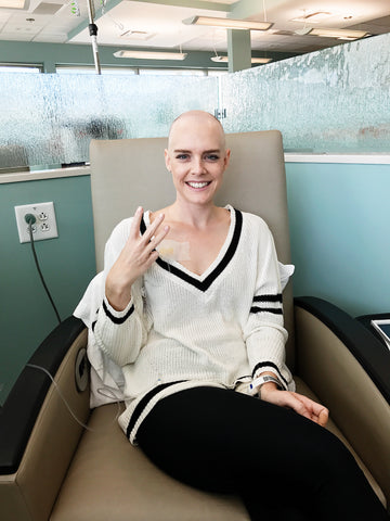 Kelsey Bucci smiling and sitting in chair at chemo appointment