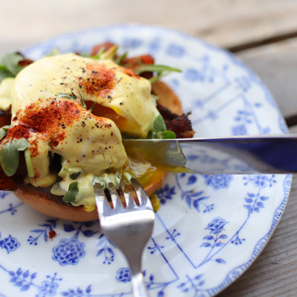Daily Kneads Bagel Hollandaise with Eggs Benedict Recipe on Blue Plate with Coffee