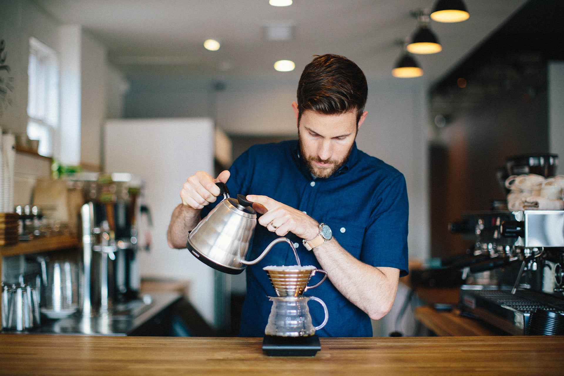 Barista pouring coffee into canter.