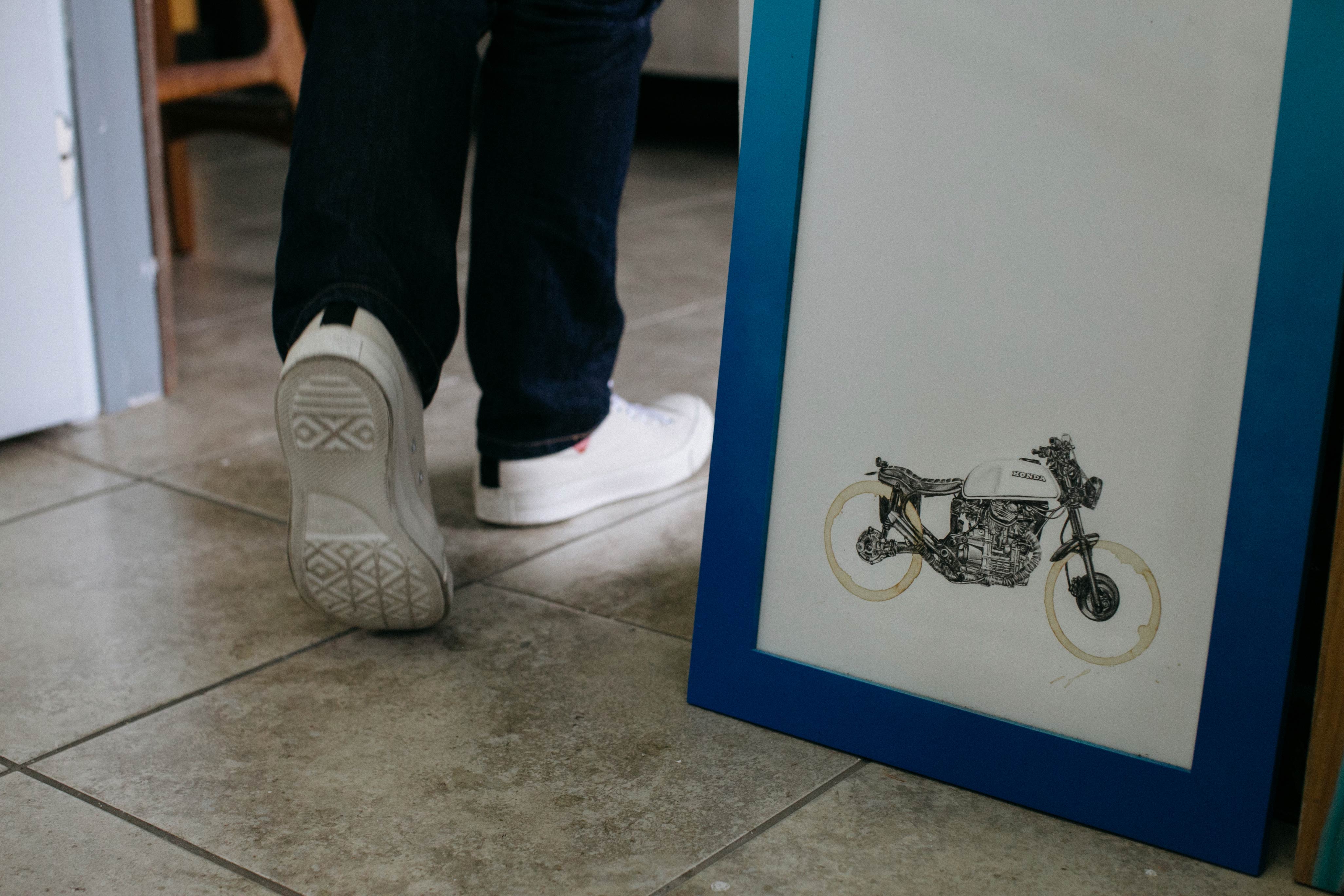 Framed print of a Carter Asmann coffee-stain motorcycle with Carter walking away from the camera in the background.