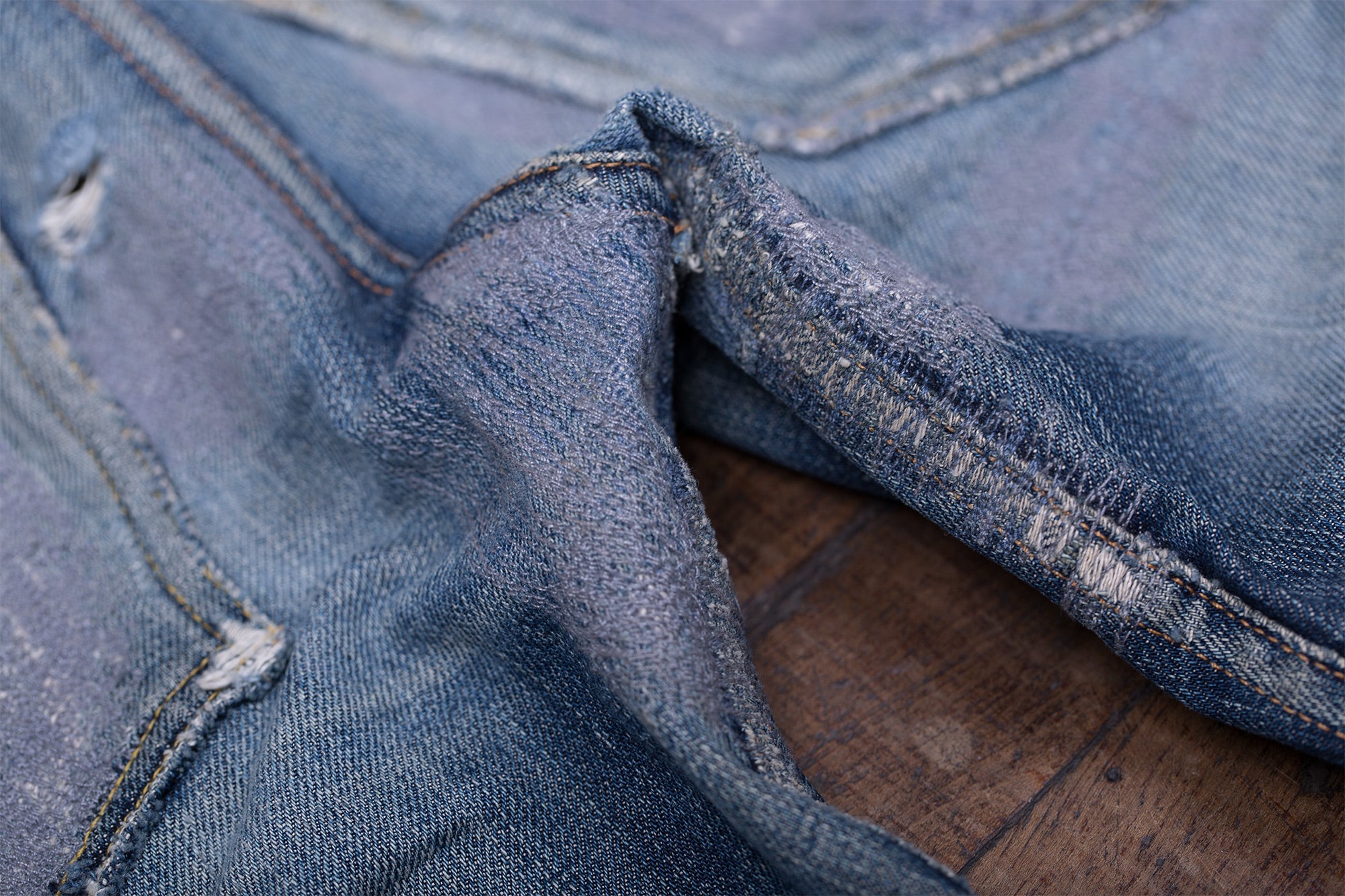 Closeup of repaired areas of the jeans where the denim has taken on a purple-ish hue.