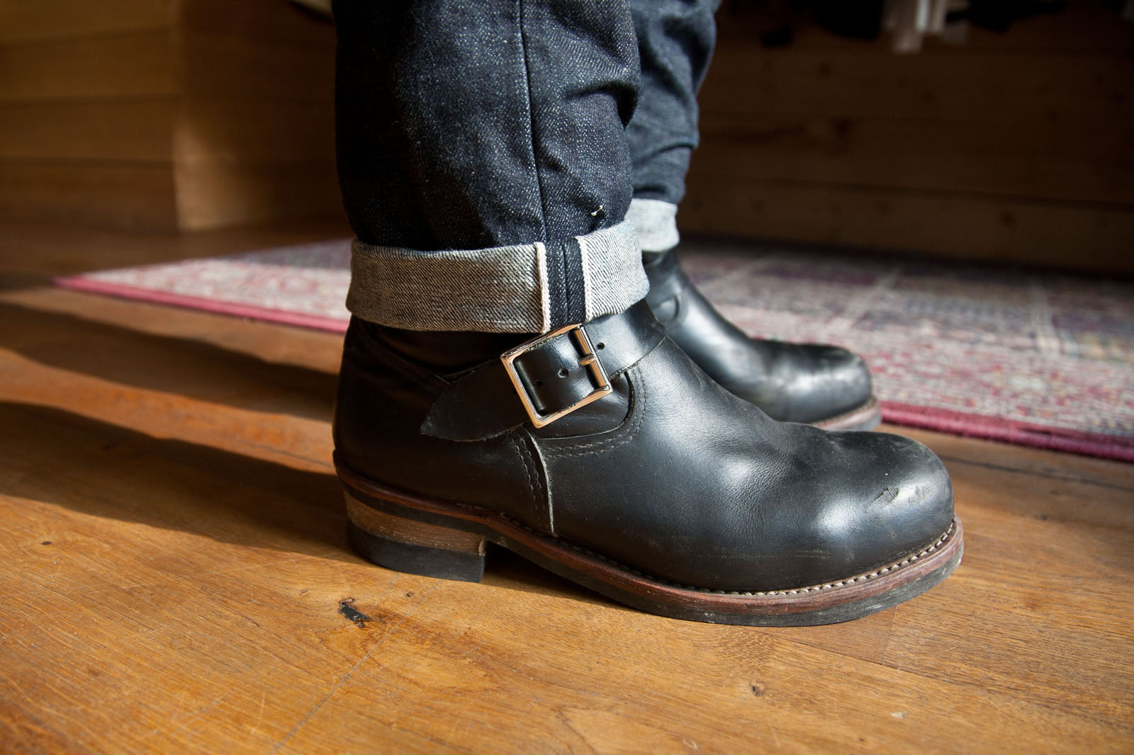 Closeup of a man wearing black engineer boots with 3sixteen denim