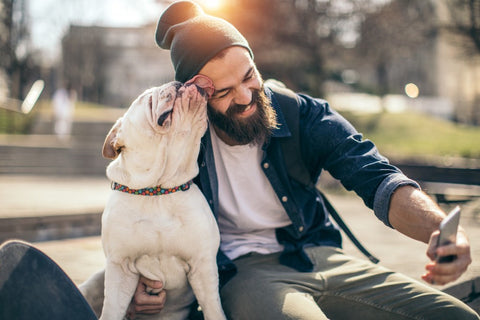 man in park with dog taking selfie