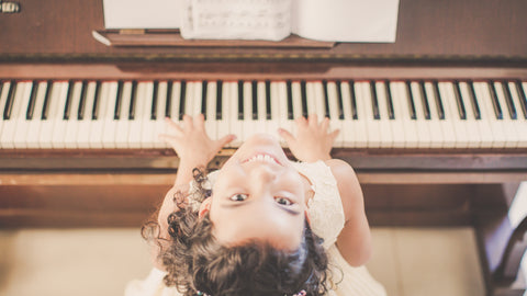 Girl looking up sitting at a piano